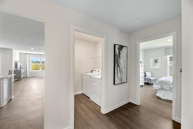 hallway featuring baseboards, dark wood-type flooring, and washer and dryer