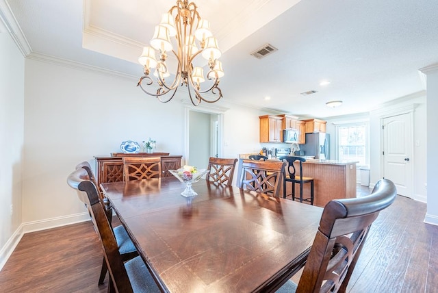 dining room with dark hardwood / wood-style flooring, ornamental molding, and a notable chandelier