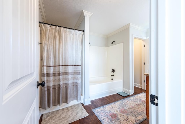 bathroom featuring a textured ceiling, hardwood / wood-style floors, shower / tub combo, and ornamental molding