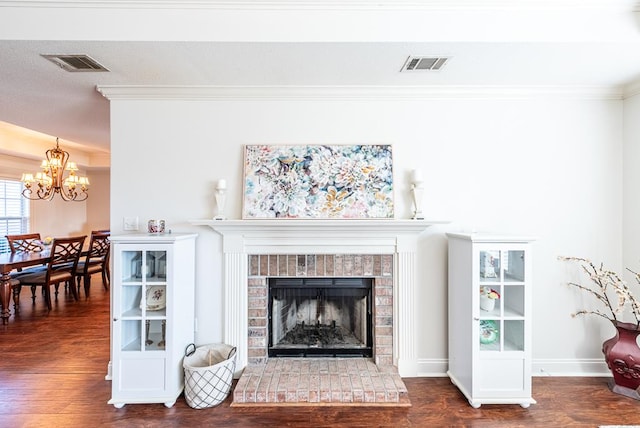 living room featuring a chandelier, dark hardwood / wood-style floors, a brick fireplace, and crown molding