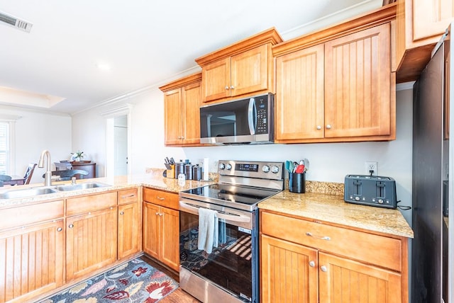 kitchen with ornamental molding, sink, appliances with stainless steel finishes, and light hardwood / wood-style flooring