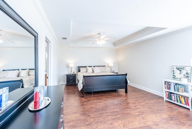 bedroom with a tray ceiling, ceiling fan, and dark wood-type flooring