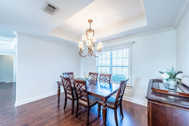 dining space featuring dark hardwood / wood-style flooring, a tray ceiling, an inviting chandelier, and crown molding