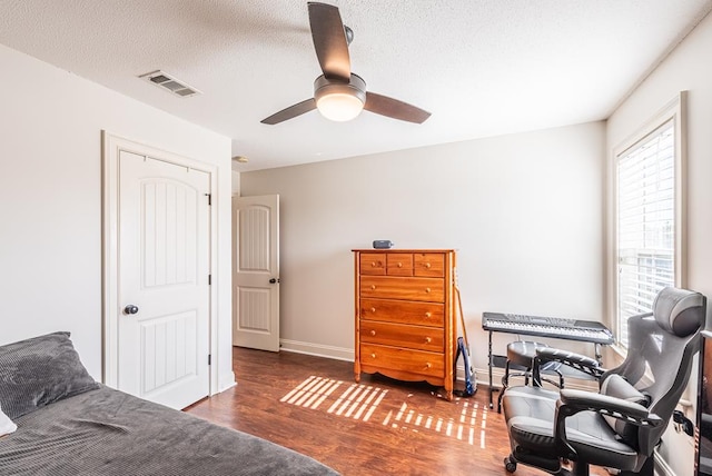 bedroom featuring a textured ceiling, dark hardwood / wood-style floors, and ceiling fan