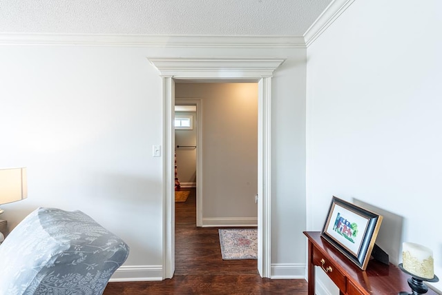 hallway with dark wood-type flooring, a textured ceiling, and ornamental molding