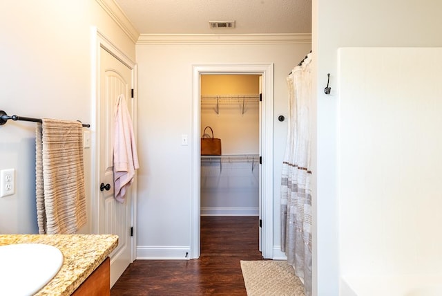 bathroom with vanity, crown molding, wood-type flooring, and a textured ceiling