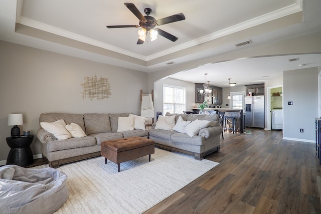 living room featuring a tray ceiling, crown molding, and dark hardwood / wood-style flooring