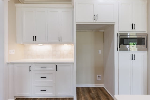 4856 Brown Cat Cir, Hahira, GA 31632 - kitchen with stainless steel microwave, decorative backsplash, light countertops, white cabinetry, and dark wood-type flooring