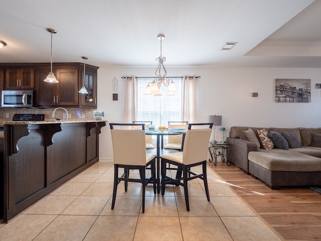 tiled dining area with crown molding, sink, a notable chandelier, and a tray ceiling