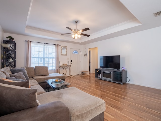 living room with crown molding, ceiling fan, a raised ceiling, and light hardwood / wood-style flooring