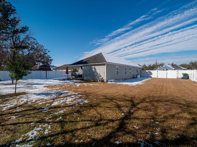 snow covered rear of property featuring a yard