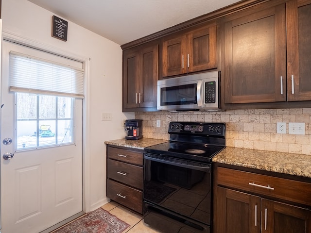 kitchen with light tile patterned floors, black range with electric stovetop, dark brown cabinetry, light stone countertops, and decorative backsplash