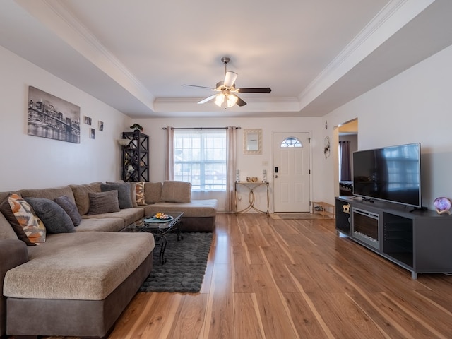 living room with hardwood / wood-style flooring, ceiling fan, crown molding, and a raised ceiling