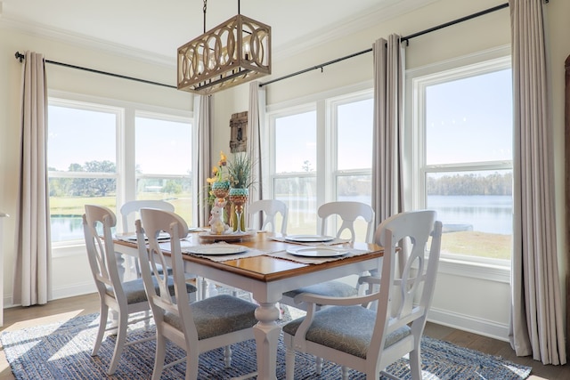 dining area with wood-type flooring, a water view, and crown molding