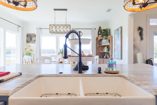 kitchen with sink, decorative light fixtures, and ornamental molding