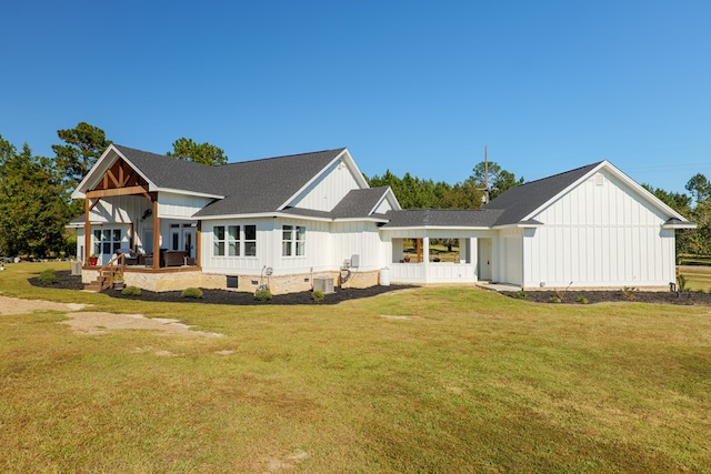 rear view of property featuring a yard, cooling unit, and covered porch