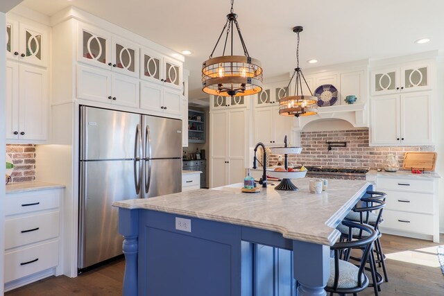 kitchen with a center island with sink, white cabinetry, stainless steel appliances, and a chandelier