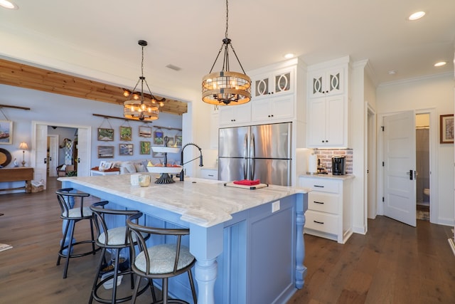 kitchen featuring white cabinetry, stainless steel fridge, a large island, and decorative light fixtures