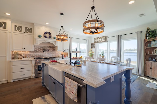 kitchen with white cabinetry, sink, stainless steel appliances, pendant lighting, and a water view