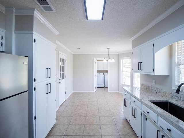 3875 Studstill Rd, Valdosta, GA 31605 - kitchen featuring freestanding refrigerator, a sink, washing machine and clothes dryer, a chandelier, and white cabinetry