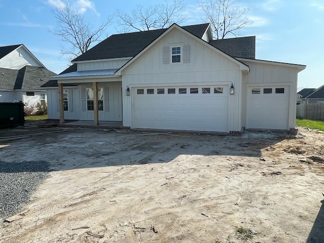 view of front of home with driveway, board and batten siding, metal roof, a shingled roof, and a garage