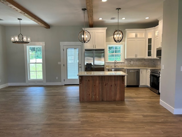 kitchen with white cabinets, beam ceiling, a center island, and stainless steel appliances