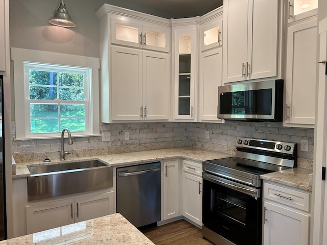 kitchen featuring white cabinetry, sink, decorative light fixtures, and appliances with stainless steel finishes