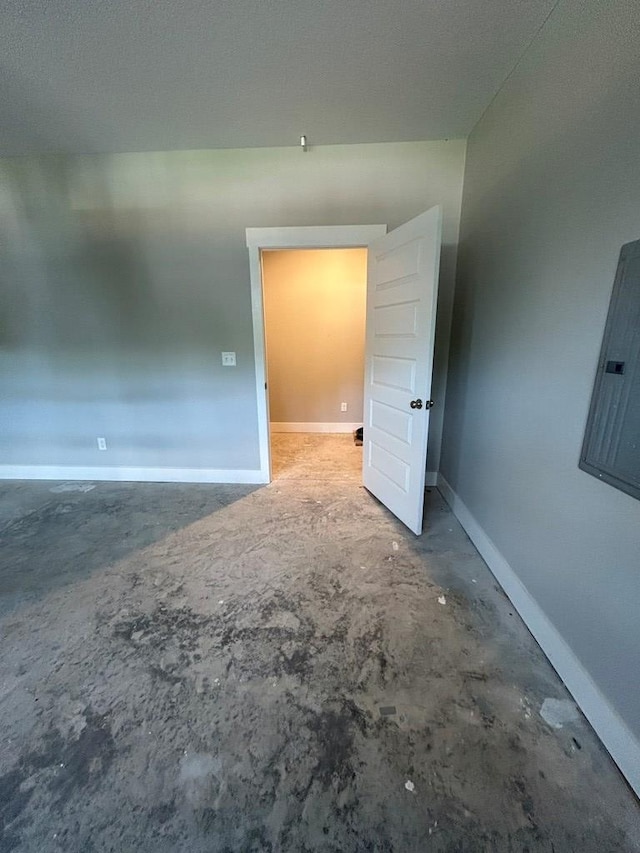 empty room with electric panel and concrete floors