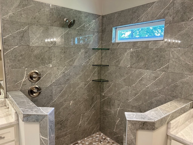 bathroom with tiled shower and vanity