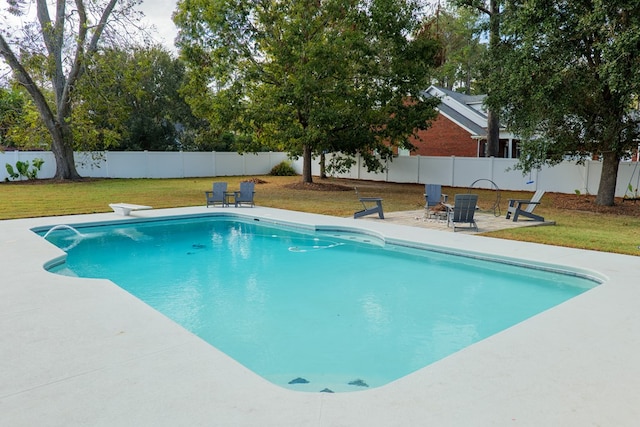 view of swimming pool featuring a lawn, a diving board, and a patio