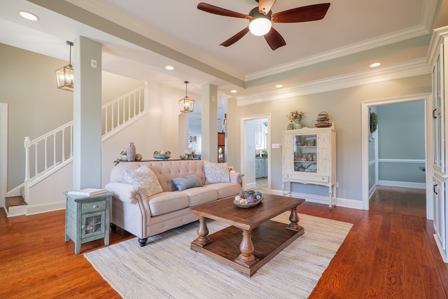 living room featuring hardwood / wood-style floors, ceiling fan with notable chandelier, and crown molding