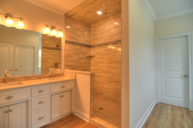 bathroom with vanity, a tile shower, wood-type flooring, and ornamental molding