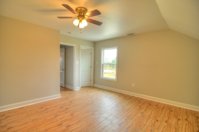 spare room with ceiling fan, light wood-type flooring, and vaulted ceiling