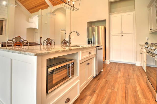 kitchen featuring ornate columns, sink, wooden ceiling, an island with sink, and appliances with stainless steel finishes