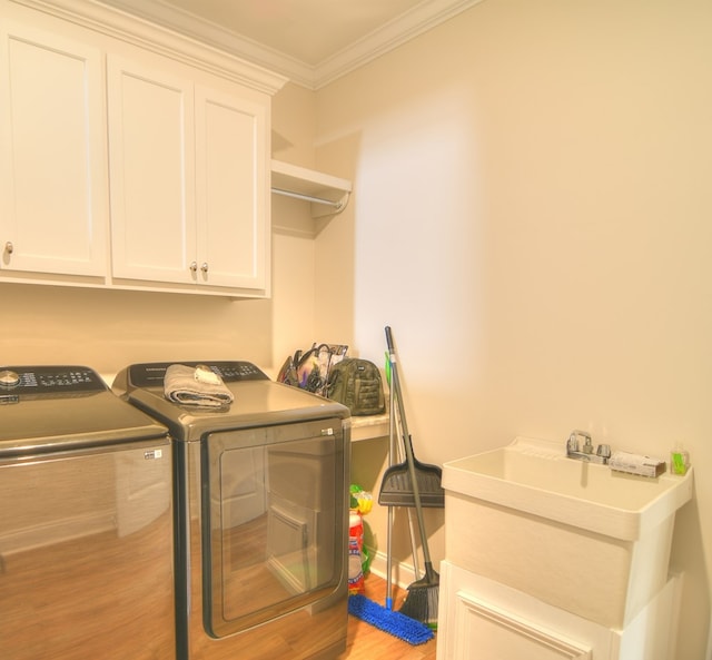 laundry area with washer and dryer, light hardwood / wood-style floors, cabinets, and crown molding