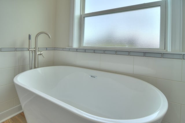 bathroom with a bathing tub, a healthy amount of sunlight, and tile walls