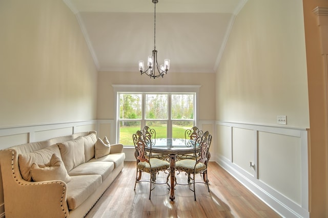 dining room with vaulted ceiling, an inviting chandelier, light hardwood / wood-style flooring, and ornamental molding