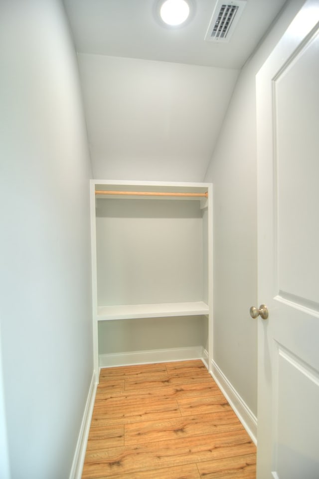 walk in closet with vaulted ceiling and light hardwood / wood-style flooring