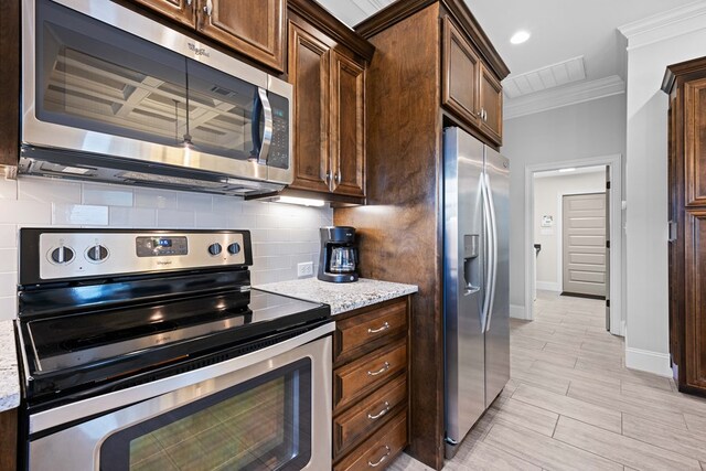 4740 Amelia Cir, Hahira, GA 31632 - kitchen with appliances with stainless steel finishes, crown molding, backsplash, dark brown cabinets, and baseboards