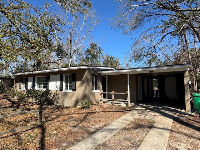 view of front of property featuring a carport, stucco siding, and driveway