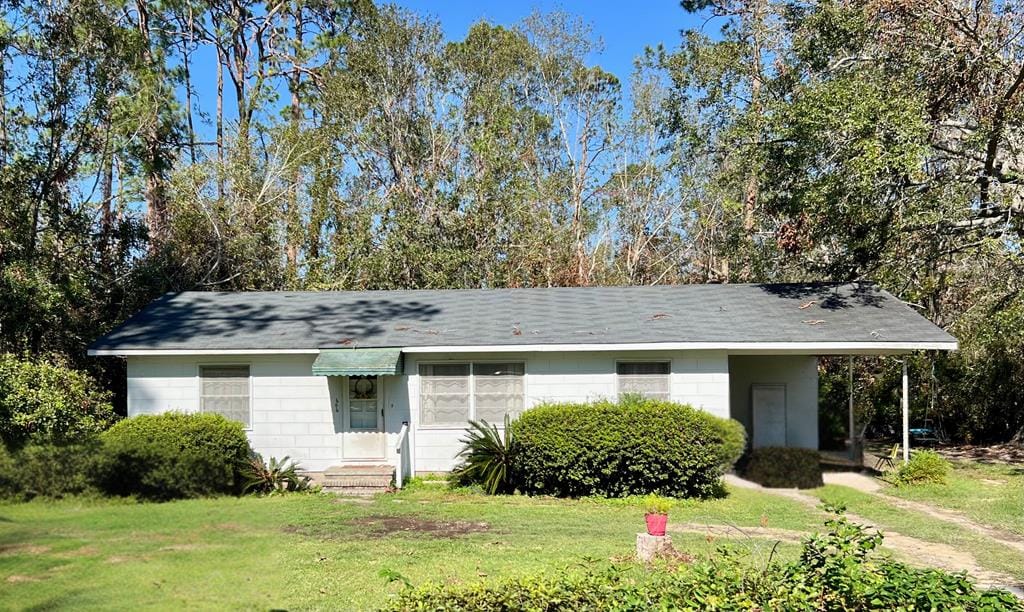 ranch-style home featuring a carport and a front lawn