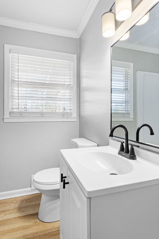 half bathroom featuring toilet, vanity, crown molding, and wood finished floors