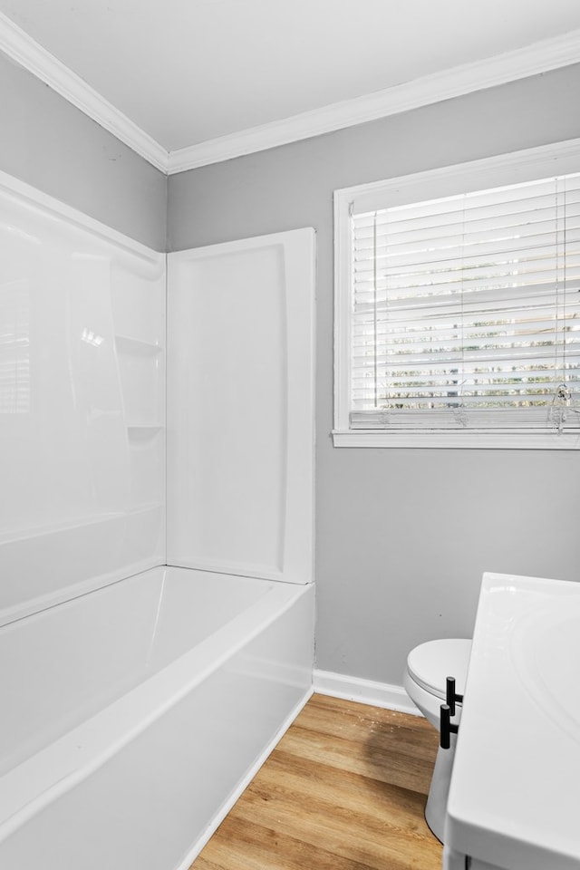 bathroom featuring ornamental molding, a tub, baseboards, and wood finished floors