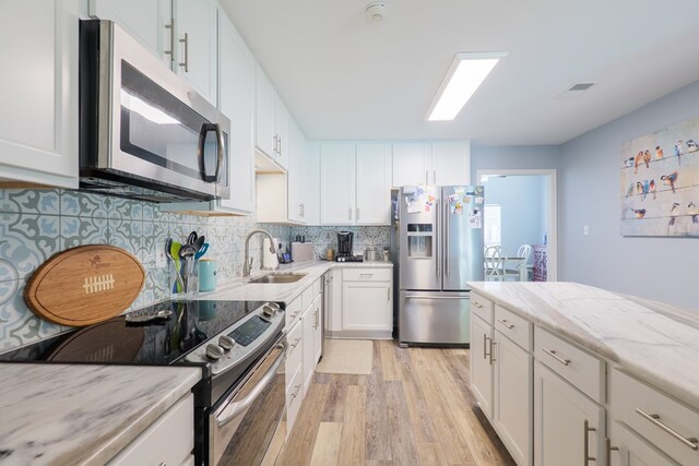 4604 Rustic Ridge Rd, Valdosta, GA 31602 - kitchen with appliances with stainless steel finishes, light wood finished floors, decorative backsplash, white cabinetry, and light stone countertops