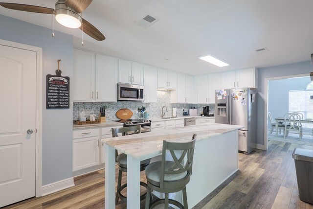 4604 Rustic Ridge Rd, Valdosta, GA 31602 - kitchen with stainless steel appliances, tasteful backsplash, white cabinets, and light wood-style floors