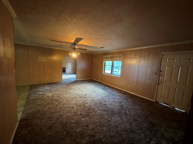 carpeted spare room with ceiling fan and wood walls