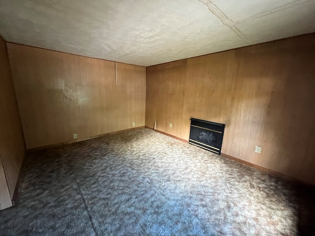 unfurnished living room featuring dark carpet, a textured ceiling, and wooden walls