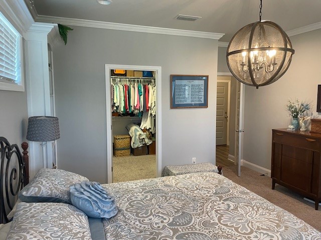 4686 Rudy Way, Hahira, GA 31632 - carpeted bedroom with a chandelier, ornamental molding, a walk in closet, a closet, and baseboards