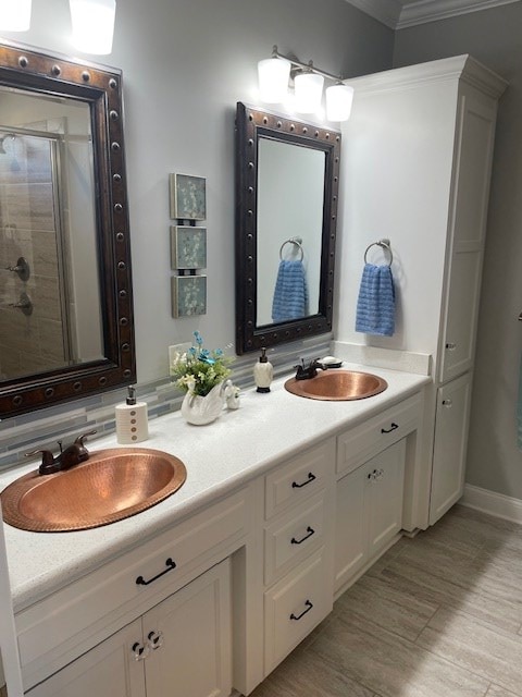 4686 Rudy Way, Hahira, GA 31632 - bathroom with double vanity, a stall shower, crown molding, wood finished floors, and baseboards