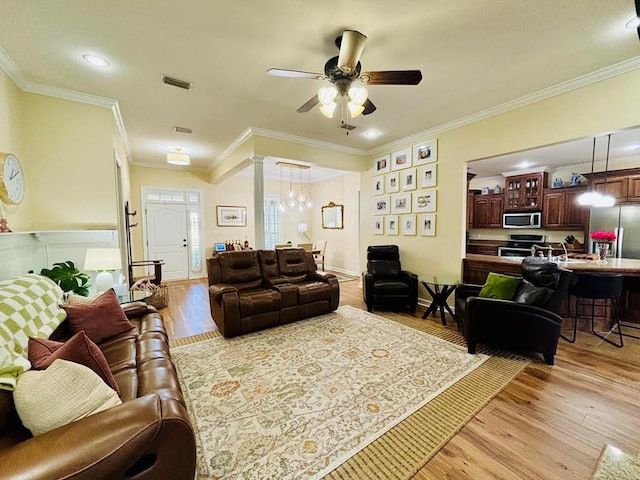 living area featuring visible vents, light wood-style flooring, ceiling fan with notable chandelier, and ornamental molding